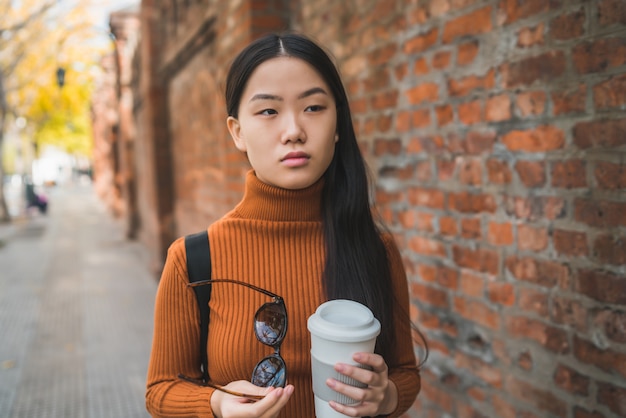 Azjatycka kobieta trzyma filiżankę kawy.