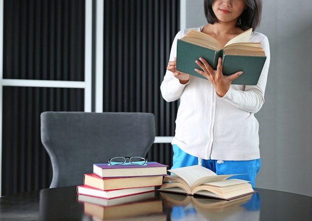 Azjatycka kobieta trzyma książkę i czyta czytać w bibliotece.