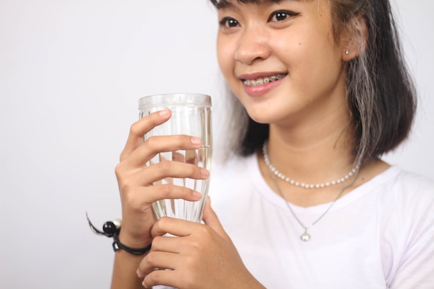 Azjatycka kobieta trzyma szklankę wody na białym tle na białym tle