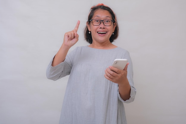 Azjatycka kobieta trzyma telefon komórkowy uśmiechnięty pogodny wyrażenie