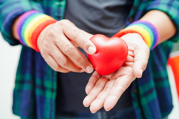 Azjatycka kobieta trzymająca czerwony hert z tęczową flagą Prawa do symboli LGBT i równość płci Miesiąc dumy LGBT w czerwcu