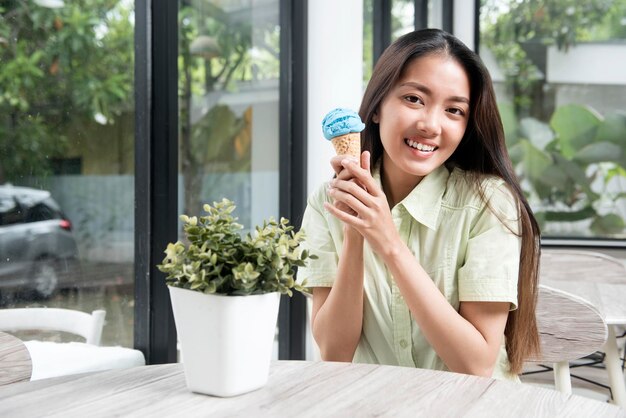 Azjatycka kobieta trzymająca lody jagodowe w kawiarni