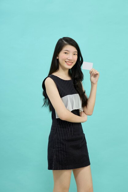 Azjatycka kobieta uśmiecha się pokazując kartę kredytową w celu dokonania płatności lub zapłaty za biznes online