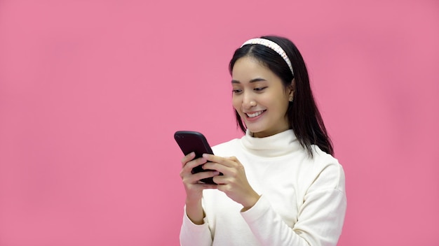 Azjatycka kobieta uśmiechająca się i korzystająca z telefonu komórkowego z tabletem i podekscytowana zakupami online na izolowanym różowym tle
