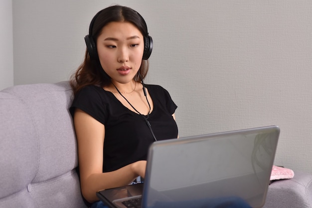 Azjatycka kobieta używa laptopa na kanapie