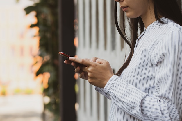 Azjatycka kobieta używa smartphone pracuje, bawić się w czasie wolnym z relaksem i szczęśliwym.