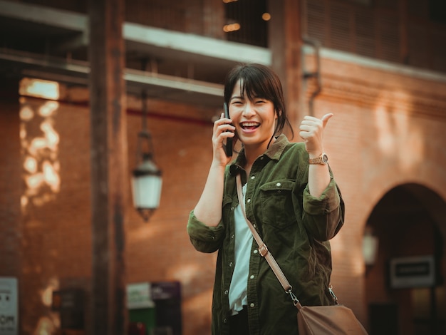 Azjatycka kobieta używa smartphone z szczęśliwym nastrojem w zakupy centrum handlowym