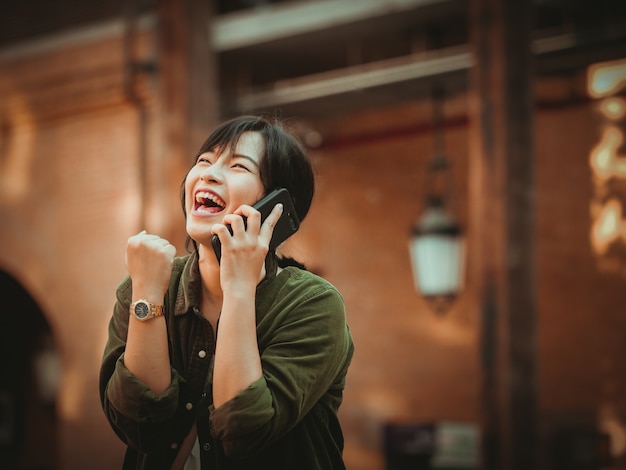 Azjatycka kobieta używa smartphone z szczęśliwym nastrojem w zakupy centrum handlowym
