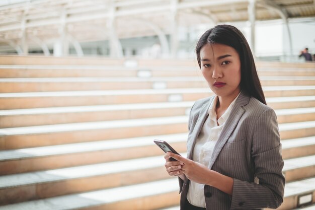 Azjatycka kobieta używa telefon komórkowego, smartphone przy miasto budynkiem