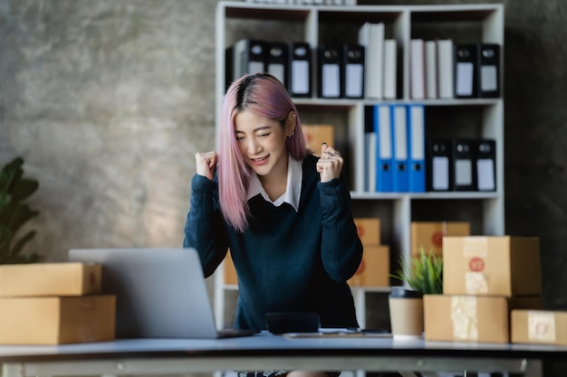 Azjatycka kobieta używająca laptopa z pudełkiem Młody sukces Azjatycka kobieta z ręką unosi pudełko do marketingu online Koncepcja MŚP