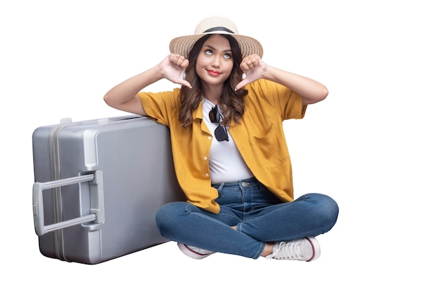 Azjatycka kobieta w kapeluszu i walizce siedzi z nieszczęśliwym wyrazem twarzy