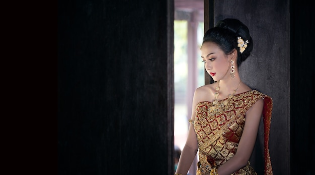 Azjatycka kobieta w tradycyjnym stroju tajskim stojącej przy oknie