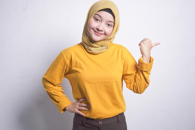 Azjatycka kobieta w żółtej koszuli wskazuje palcami na bok