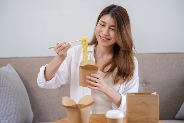 Azjatycka kobieta z jedzeniem i napojami na wynos w konsumpcji domowej, jedząca jedzenie z dostawą do domu