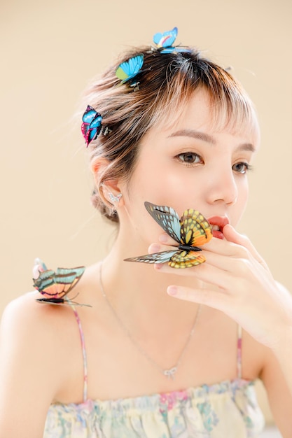 Azjatycka kobieta z piękną twarzą i idealnie czystą świeżą skórą Portret modelki z motylem i błyszczącymi oczami na beżowym na białym tle Kosmetologia Pielęgnacja ciała Chirurgia plastyczna