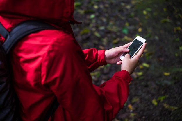 Zdjęcie azjatycka kobieta z plecakiem używać smartphone podczas trekking wycieczki w tropikalnym lesie deszczowym.