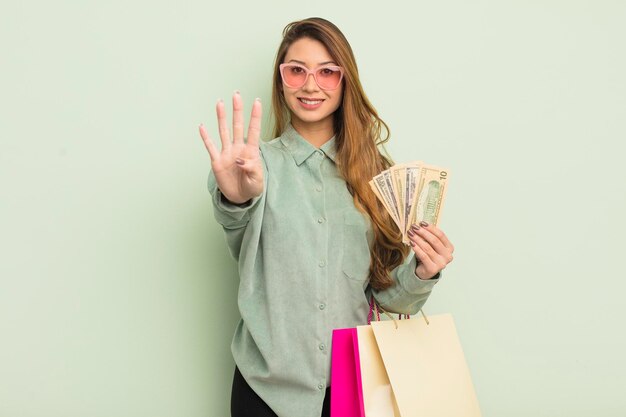 Azjatycka ładna kobieta uśmiechnięta i wyglądająca przyjaźnie, pokazująca koncepcję toreb na zakupy numer cztery