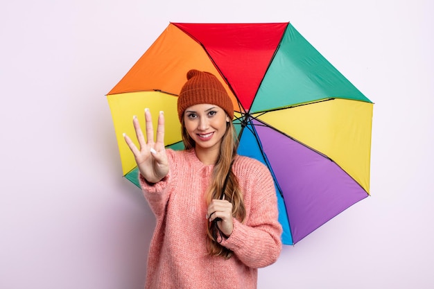Azjatycka ładna kobieta uśmiechnięta i wyglądająca przyjaźnie, pokazująca numer cztery. koncepcja parasola