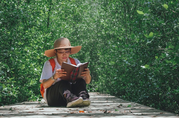 Azjatycka leśniczka siedzi na chodniku i robi notatki w lesie namorzynowym w naturalnym parku
