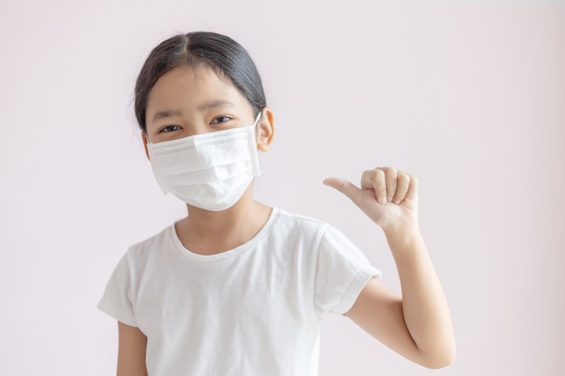 Azjatycka mała dziewczynka jest ubranym ochronną medyczną maskę