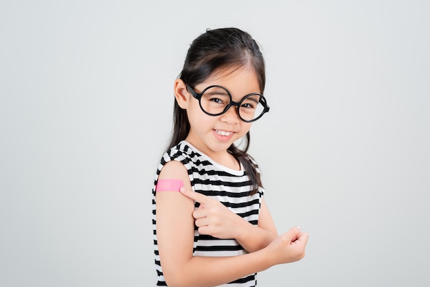 Azjatycka mała dziewczynka nosi okulary pokazujące ramię z bandażem po wirusie