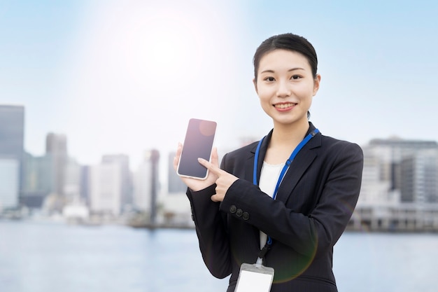 Azjatycka młoda biznesowa kobieta obsługi smartfona z uśmiechem