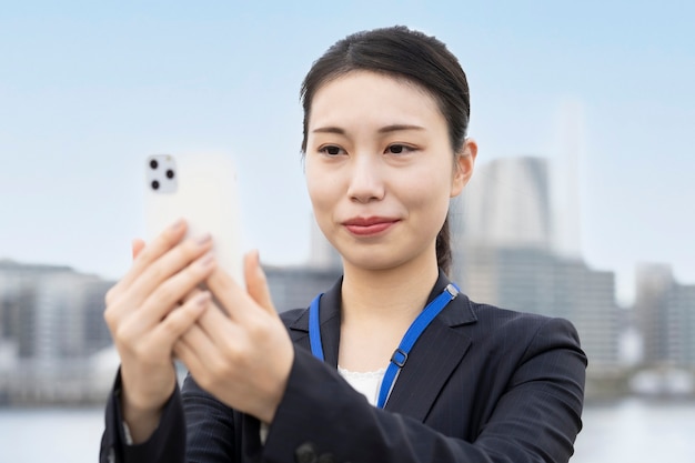 Azjatycka młoda biznesowa kobieta obsługi smartfona z uśmiechem