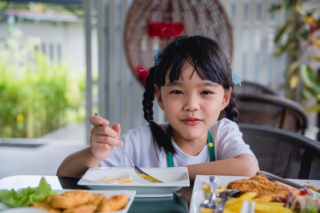 Azjatycka młoda dziewczyna azjatycka je smażone jajko na naczyniu przy stołem