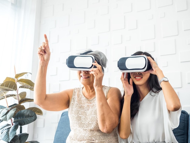 Azjatycka młoda kobieta szczęśliwa córka i jej matka stara starsza kobieta w okularach VR cieszyć się grą 3d online razem w białym pokoju Mama i córka z koncepcją stylu życia technologii wirtualnej rzeczywistości