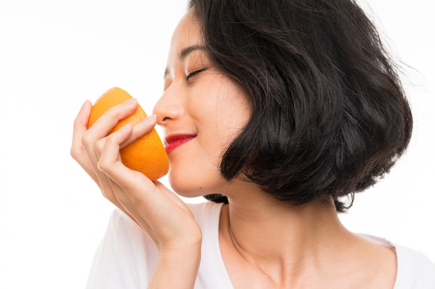 Azjatycka młoda kobieta trzyma pomarańcze nad odosobnioną ścianą