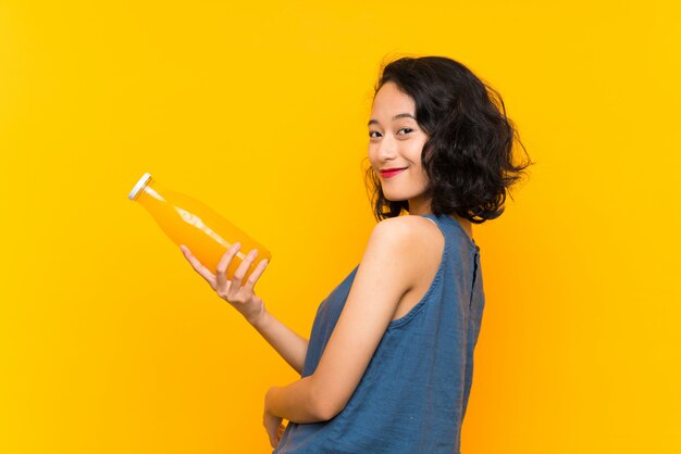Azjatycka młoda kobieta trzyma sok pomarańczowego