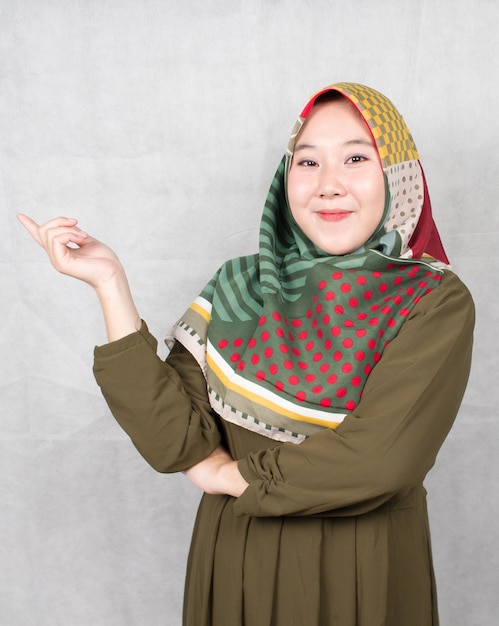 Azjatycka muzułmanka na promocji, wskazująca z uśmiechem w prawo