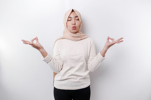 Azjatycka muzułmanka praktykująca jogę i medytująca pozę z zamkniętymi oczami odizolowanymi białym tłem