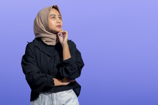 Azjatycka Muzułmanka z wyrazem twarzy próbującym zrozumieć palec na policzku, patrząc w prawo na białym tle