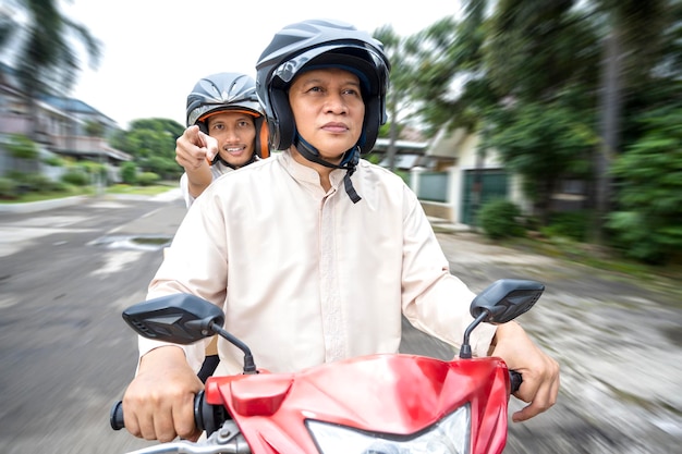 Azjatycka muzułmańska rodzina niosąca pudełko na motocyklu jadącym mudik