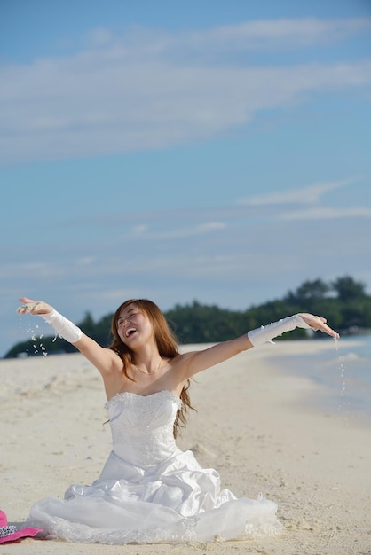 azjatycka panna młoda z welonem na plaży na niebie i błękitnym morzu. miesiąc miodowy na fantastycznej wyspie latem