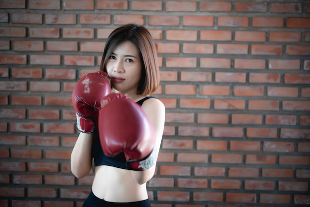 Azjatycka piękna kobieta nosi rękawice bokserskie na siłowni
