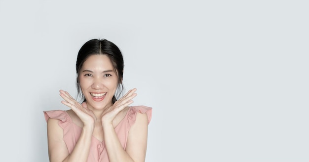 Azjatycka piękna kobieta podnosi obie ręce obok twarzy i uśmiecha się ze szczęścia
