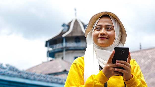 Azjatycka podróżniczka z aparatem trzymając telefon