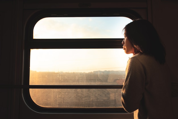Azjatycka podróżnik kobieta wygląda przez okno jadącego pociągu