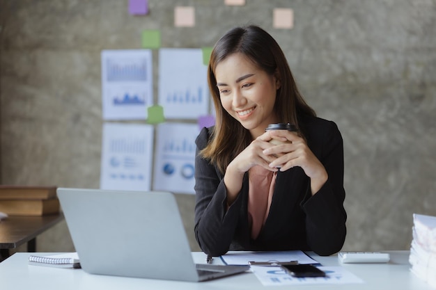 Azjatycka pracownica siedzi z filiżanką kawy w biurze działu marketingu startupu, jest łącznikiem z klientem marketingowym i pracownikiem konsultingowym Koncepcja marketingowa