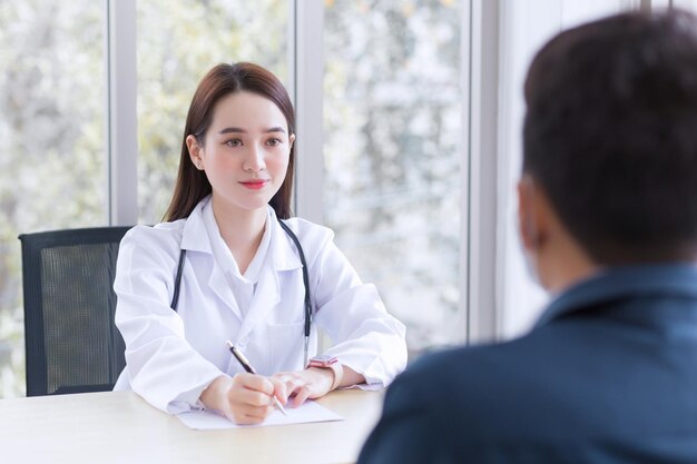 Azjatycka profesjonalna lekarka, która nosi płaszcz medyczny, rozmawia z pacjentem, aby się skonsultować
