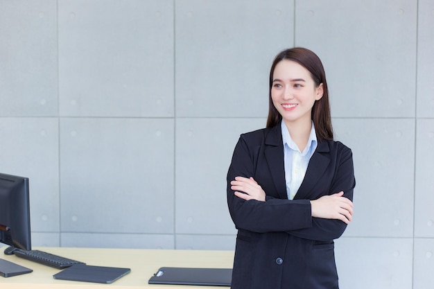 Azjatycka profesjonalna pracująca kobieta, która ma długie włosy, nosi czarny formalny garnitur w pokoju biurowym