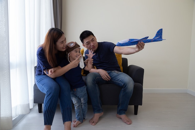 Azjatycka Rodzina I 3-letni Syn Bawią Się Samolocikiem I Siedzą Na Kanapie W Salonie W Domu