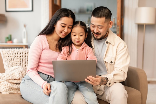 Azjatycka rodzina korzystająca z laptopa odkrywająca cyfrowy świat siedząca w domu