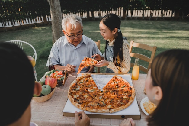 Azjatycka rodzina o pizzę w ogrodzie w domu. Rodzic ze stylem życia dziecka i dziadka na podwórku.