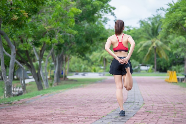 Azjatycka sportowa kobieta rozciągająca ciało oddychając świeżym powietrzem w parkuTajlandczycyKoncepcja fitnessu i ćwiczeńjogging w parku