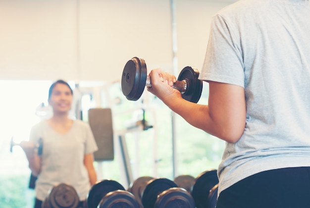 Azjatycka sprawności fizycznej kobieta robi podnoszenie ciężarów dla ćwiczenia w gym