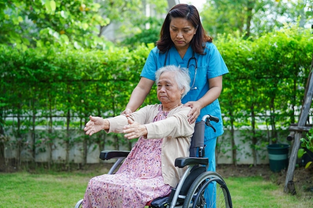 Azjatycka starsza kobieta niepełnosprawna pacjentka na wózku inwalidzkim z lekarzem w koncepcji medycznej w parku