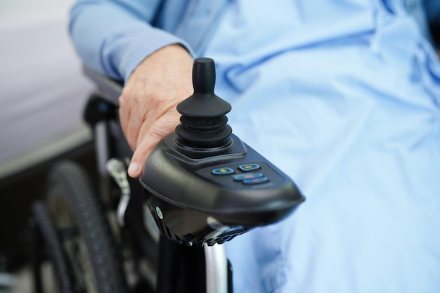Azjatycka starsza kobieta niepełnosprawna pacjentka siedząca na elektrycznym wózku inwalidzkim w koncepcji medycznej w parku